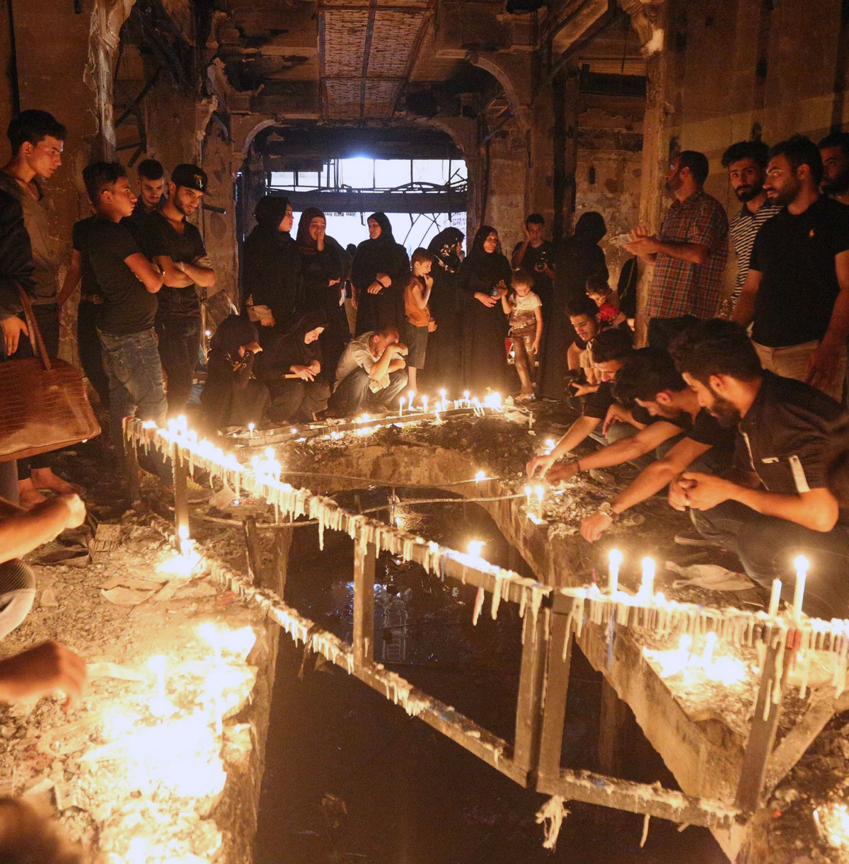 Iraqis light candles and mourn for the dead in the ruins of the Karada bombing