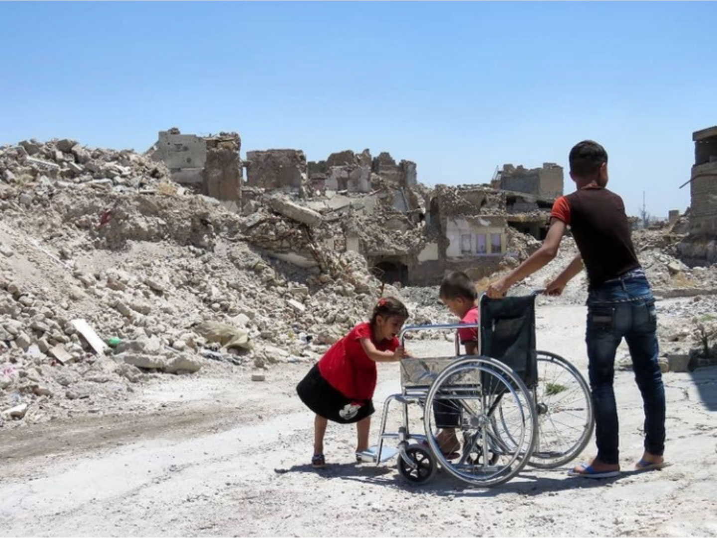 Children, one of them in a wheelchair, play among the rubble and ruins of the old part of Iraqi's Northern city of Mosul